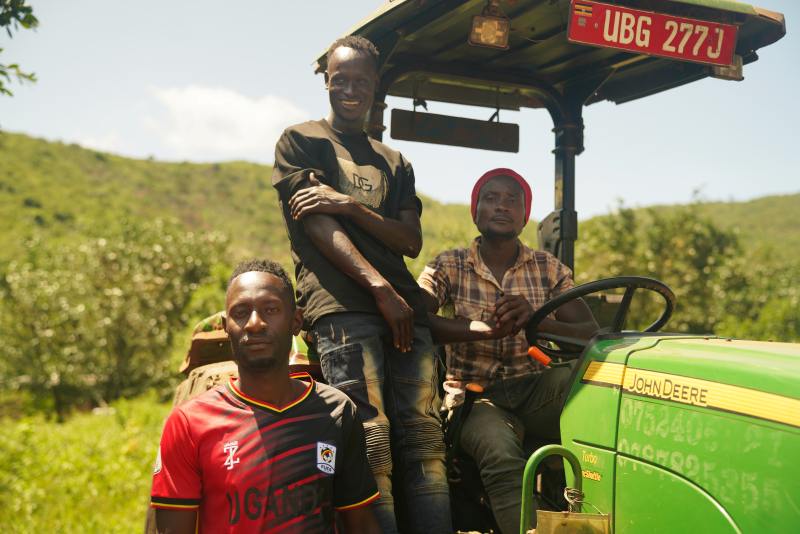 uganda farm employees sitting on tractor in field