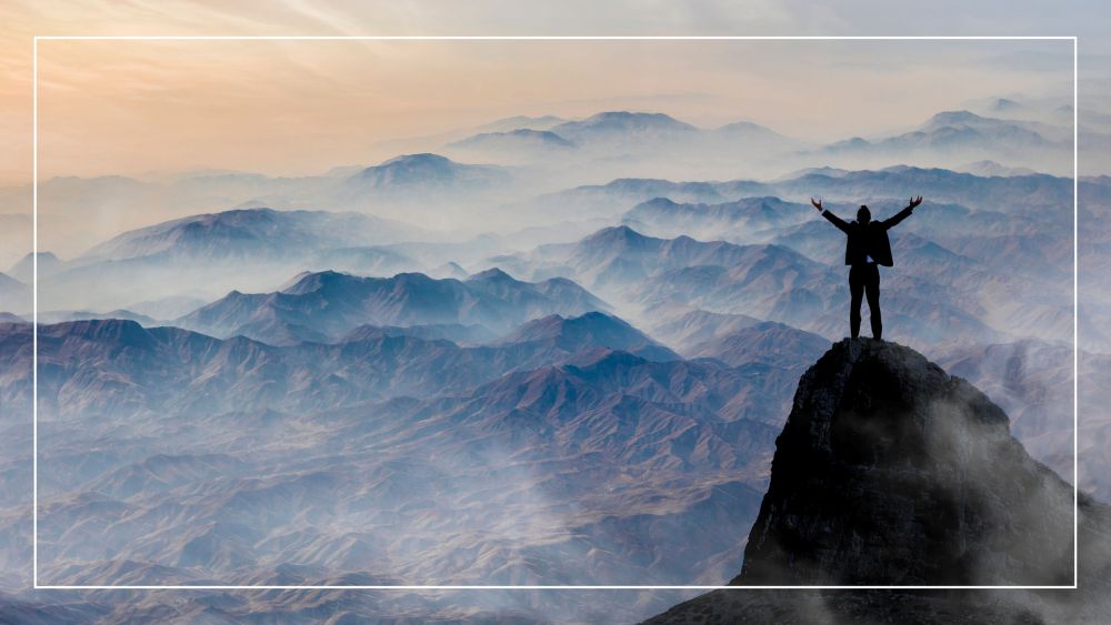 man with his arms raised on top of a mountain being thankful for the favor of god