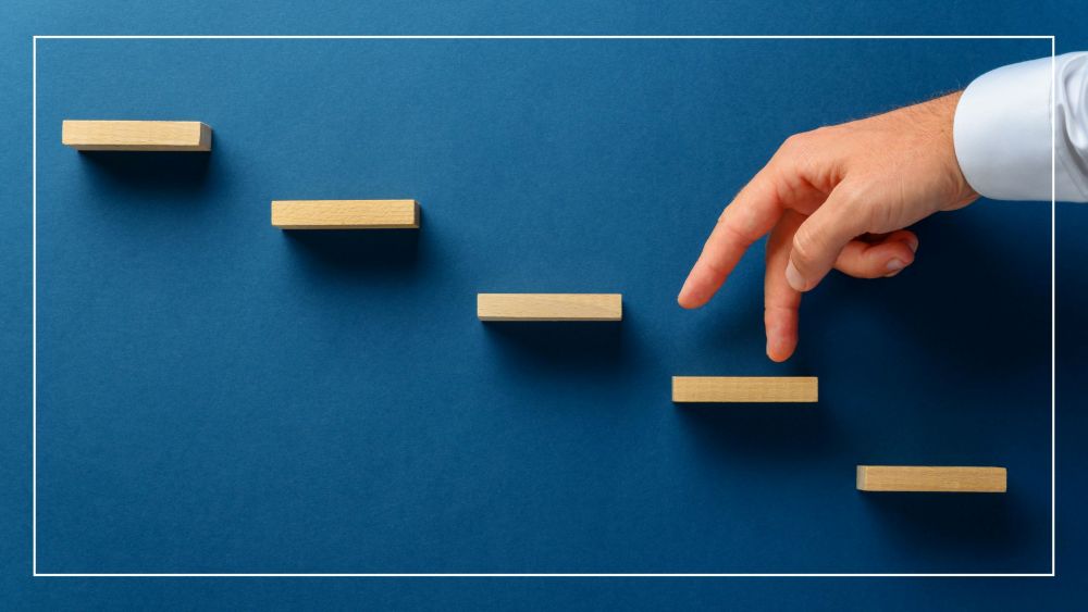 blue background with wooden steps glued to it with a man using his fingers to illustrate walking up the steps 