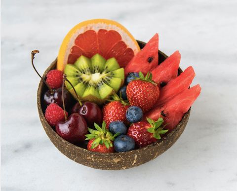 a bowl full of fruit on a white table